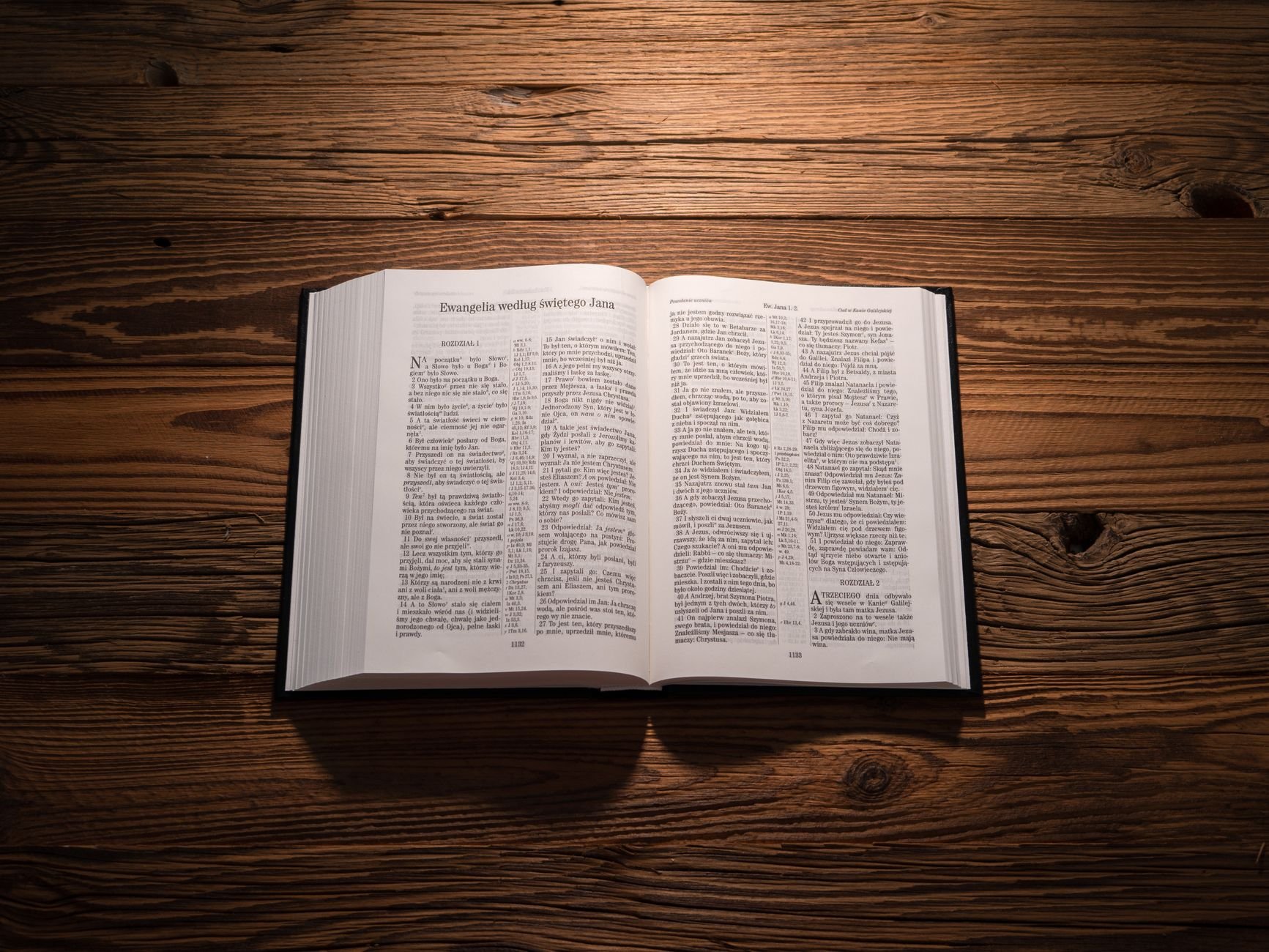 Open Bible on a wooden table under warm light, emphasizing sacred text and wood texture.